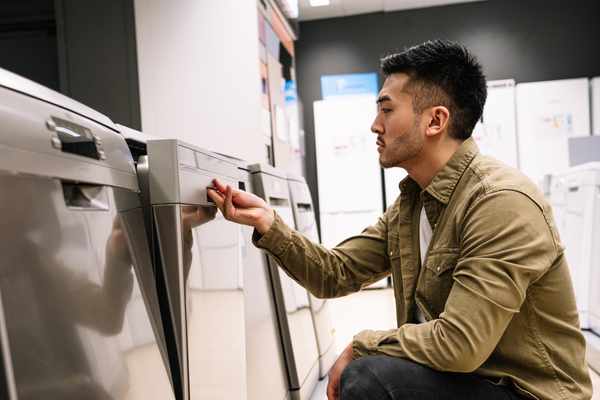 A man inspecting a dishwasher in a store